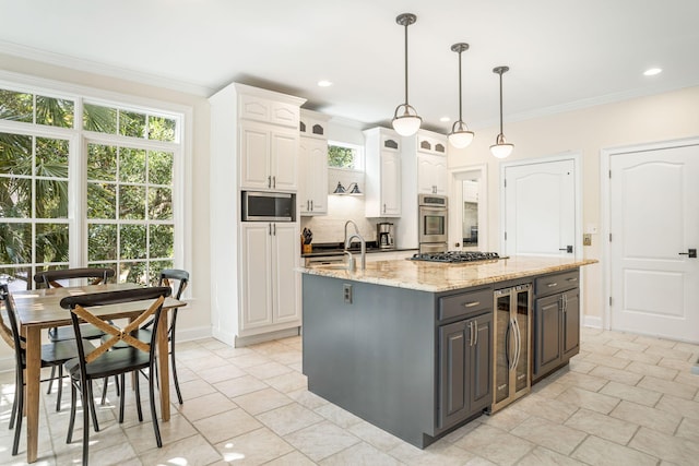 kitchen featuring wine cooler, a kitchen island with sink, white cabinets, appliances with stainless steel finishes, and light stone countertops