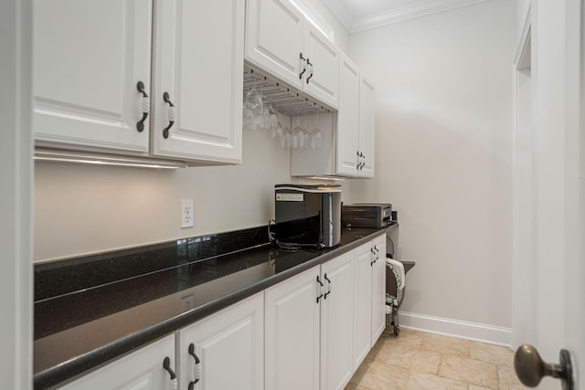 kitchen featuring dark stone counters, white cabinetry, and crown molding