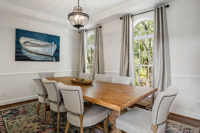 dining space with wood-type flooring, ornamental molding, plenty of natural light, and a chandelier