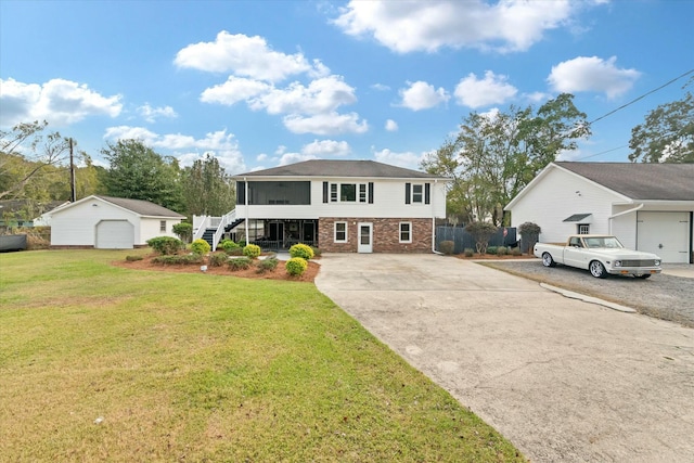 view of front of property featuring a front yard, an outbuilding, a garage, and a sunroom