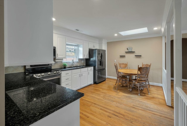 kitchen featuring a skylight, sink, white cabinets, and appliances with stainless steel finishes