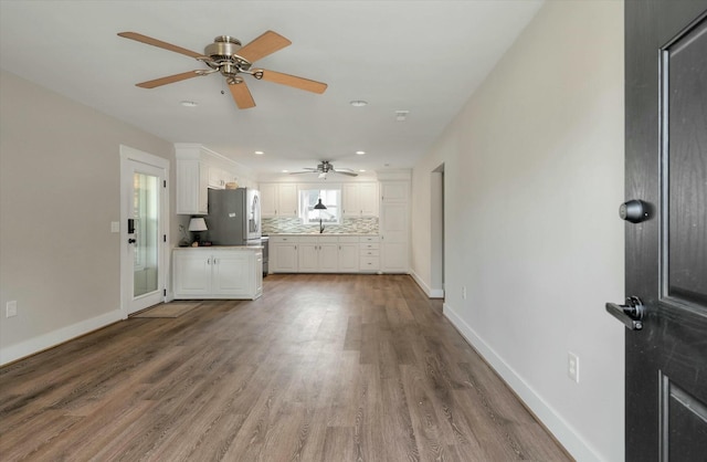 unfurnished living room with hardwood / wood-style floors, ceiling fan, and sink