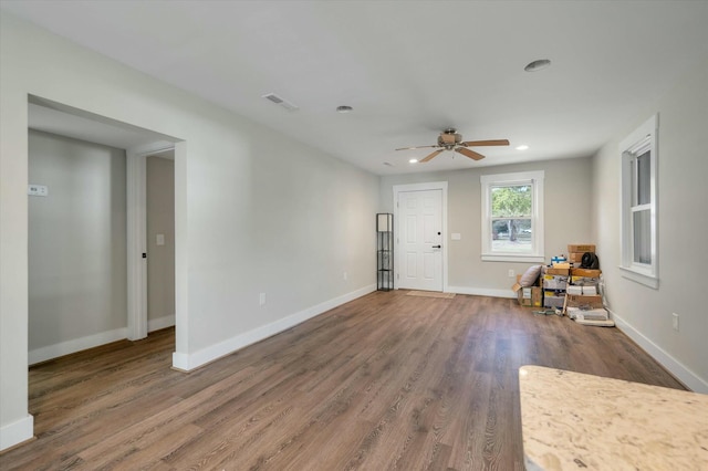 unfurnished living room with dark hardwood / wood-style flooring and ceiling fan