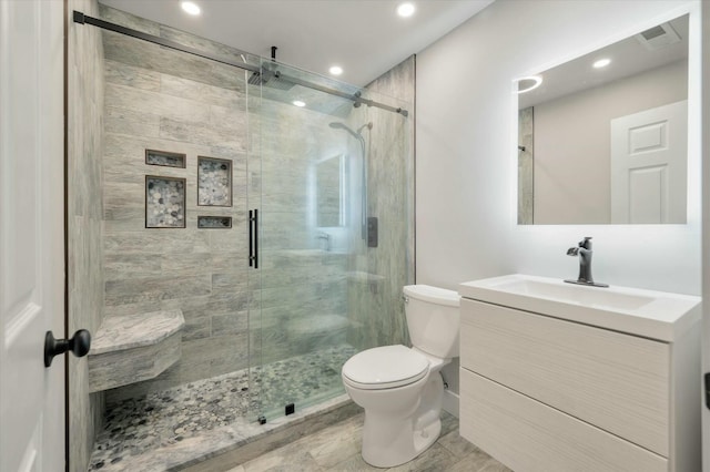 bathroom featuring vanity, toilet, and a shower with shower door