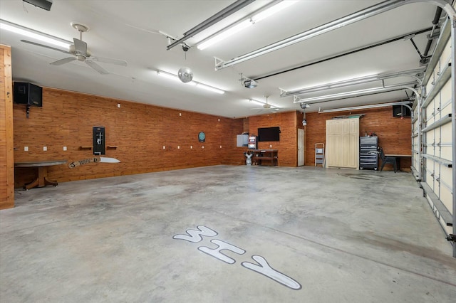 garage with ceiling fan, wood walls, and a garage door opener