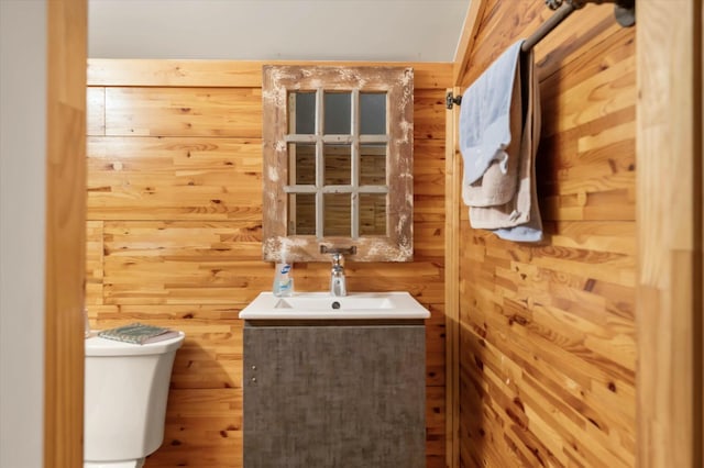 bathroom with vanity, toilet, and wooden walls