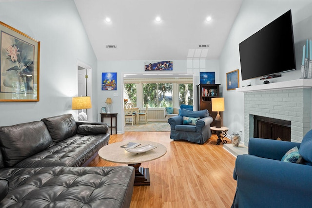 living room featuring a fireplace, wood-type flooring, and high vaulted ceiling