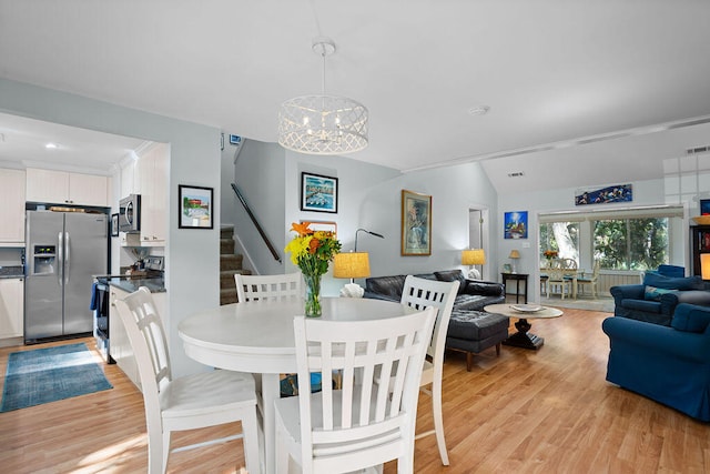 dining room with vaulted ceiling, light wood-type flooring, and an inviting chandelier