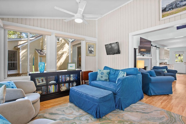 living room with ceiling fan, wood-type flooring, lofted ceiling, and wooden walls