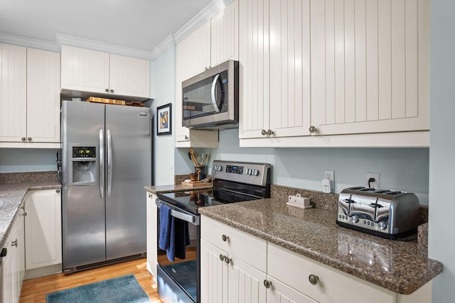 kitchen featuring light wood-type flooring, stainless steel appliances, white cabinets, dark stone countertops, and ornamental molding