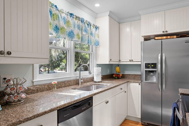 kitchen with stainless steel appliances, sink, crown molding, stone counters, and white cabinetry