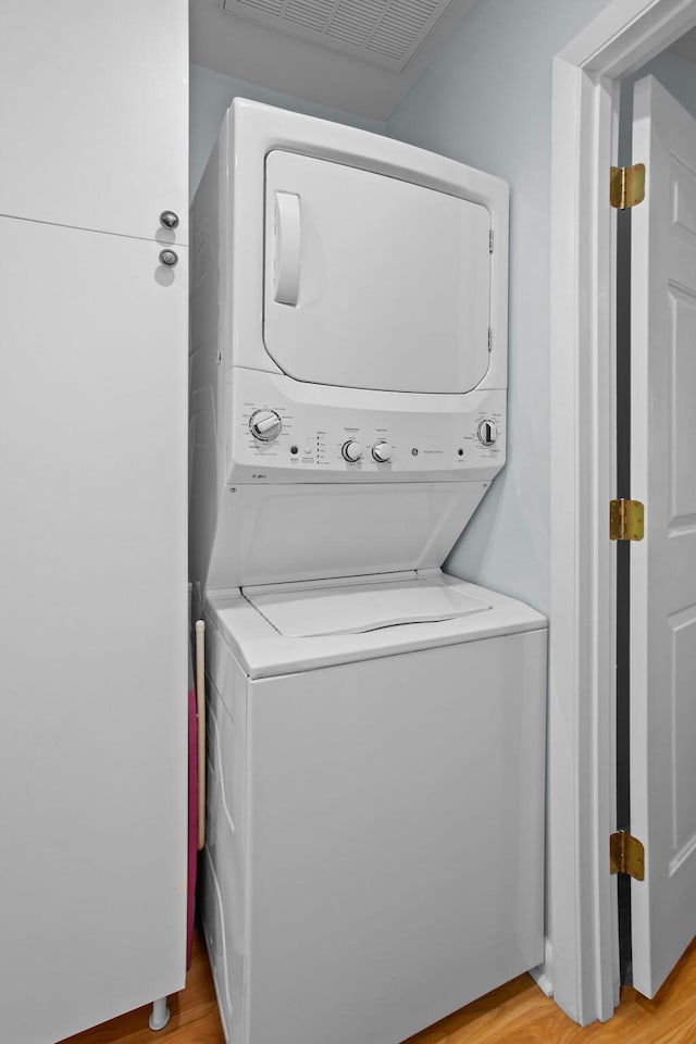 laundry area with stacked washing maching and dryer and light wood-type flooring