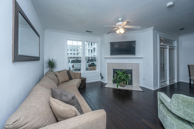 living room featuring ornamental molding, dark wood-type flooring, ceiling fan, and a fireplace