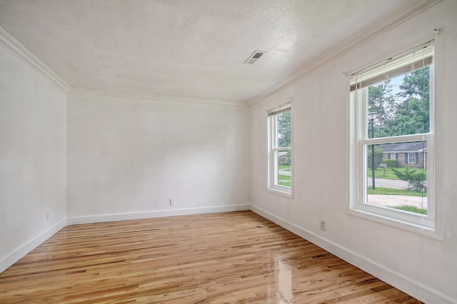 empty room with light wood-type flooring, visible vents, crown molding, and a textured ceiling