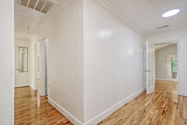 hallway with visible vents, ornamental molding, light wood-type flooring, and attic access