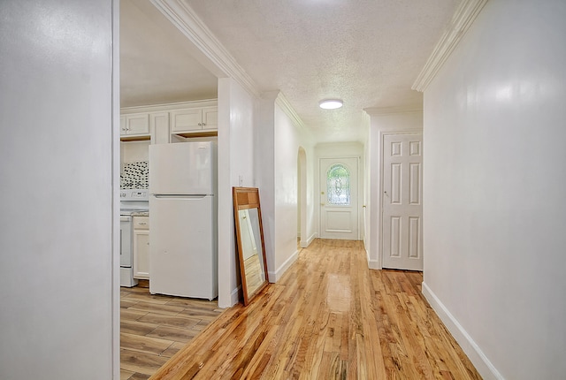 corridor featuring light wood-type flooring, arched walkways, a textured ceiling, and ornamental molding