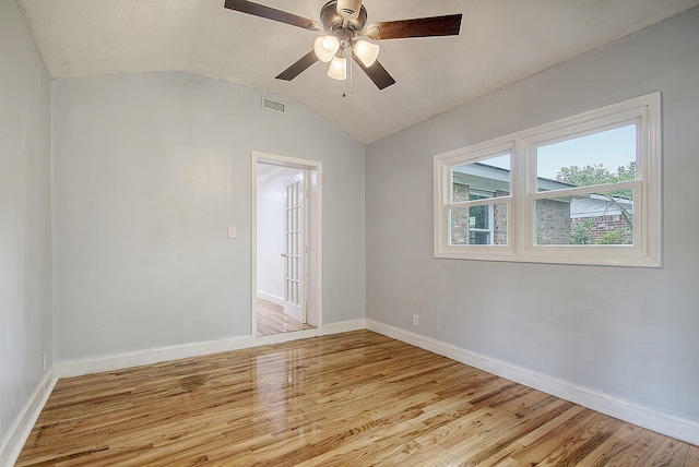 unfurnished room with visible vents, light wood-style floors, vaulted ceiling, ceiling fan, and baseboards