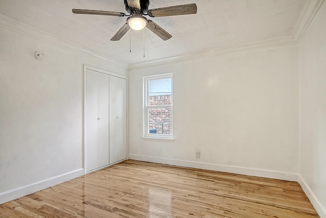 unfurnished bedroom featuring baseboards, a textured ceiling, crown molding, light wood-style floors, and a closet