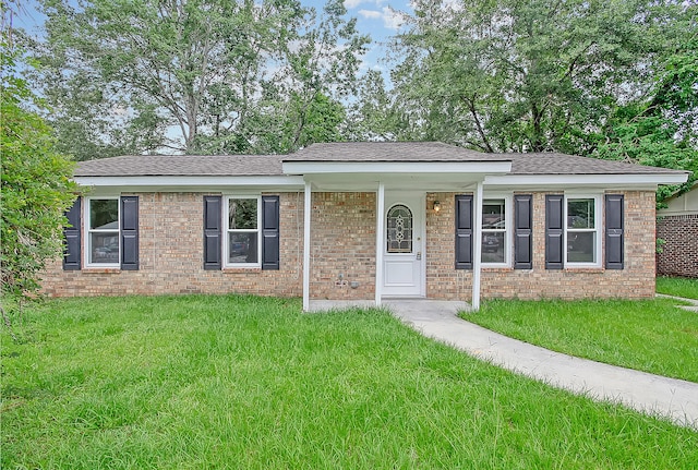 single story home featuring brick siding, a front lawn, and roof with shingles