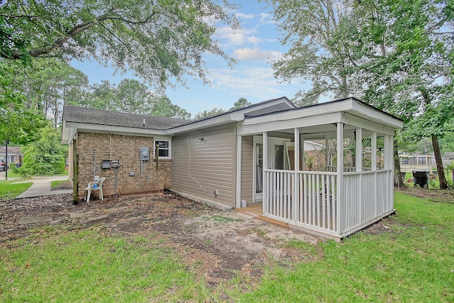 rear view of house with a yard, brick siding, and a sunroom