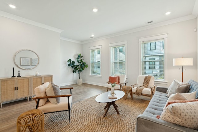 living area with light wood finished floors, baseboards, visible vents, ornamental molding, and recessed lighting