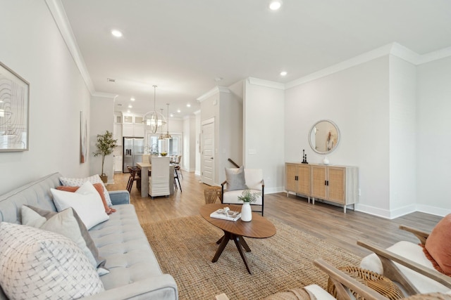 living area featuring baseboards, light wood finished floors, crown molding, and recessed lighting