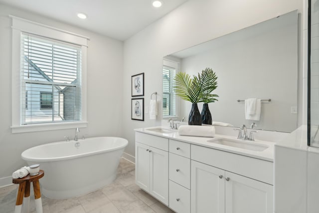 full bathroom featuring a freestanding tub, a sink, baseboards, and double vanity