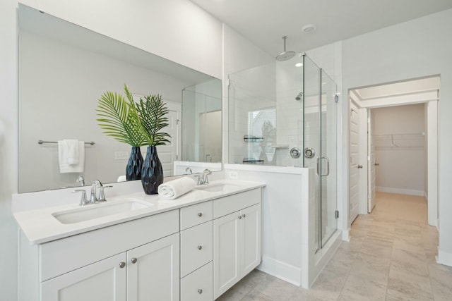 bathroom featuring double vanity, a shower stall, a walk in closet, and a sink