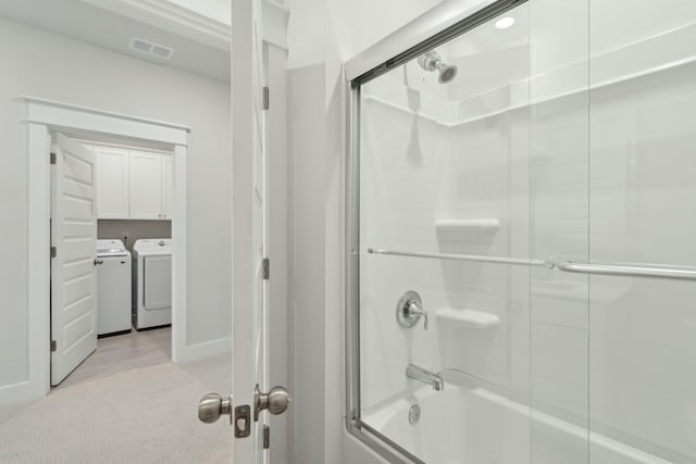 bathroom featuring combined bath / shower with glass door, washer and clothes dryer, and visible vents