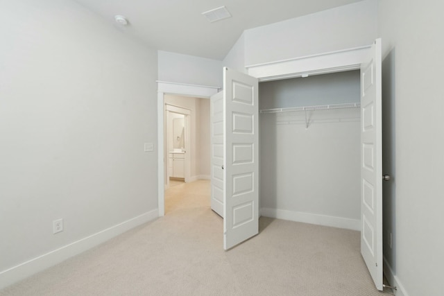 unfurnished bedroom featuring a closet, light carpet, and baseboards