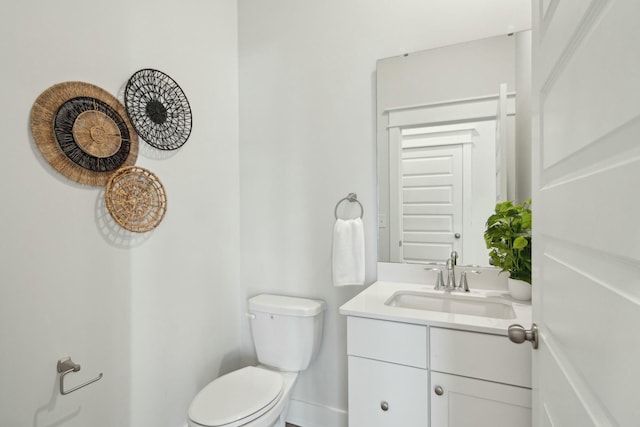 half bathroom with toilet, baseboards, and vanity