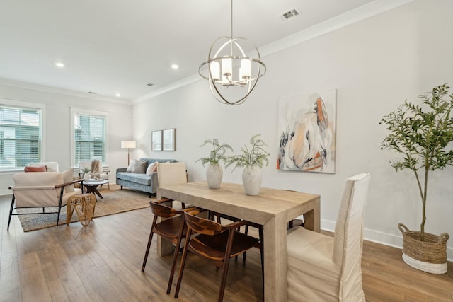 dining area featuring visible vents, a chandelier, wood finished floors, and ornamental molding