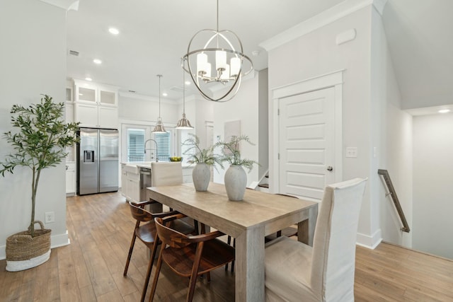 dining area featuring light wood-type flooring, an inviting chandelier, ornamental molding, and recessed lighting