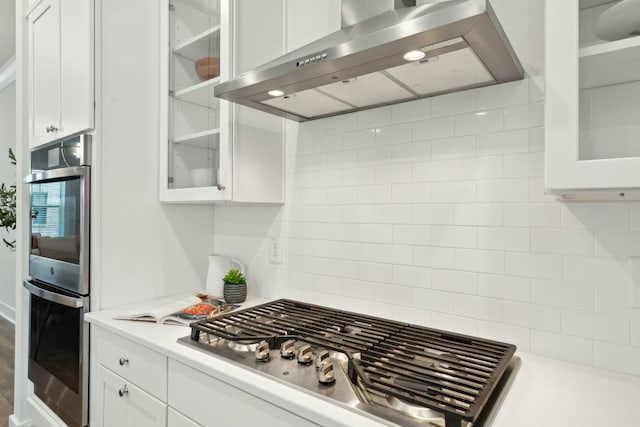 kitchen featuring light countertops, extractor fan, glass insert cabinets, and white cabinetry