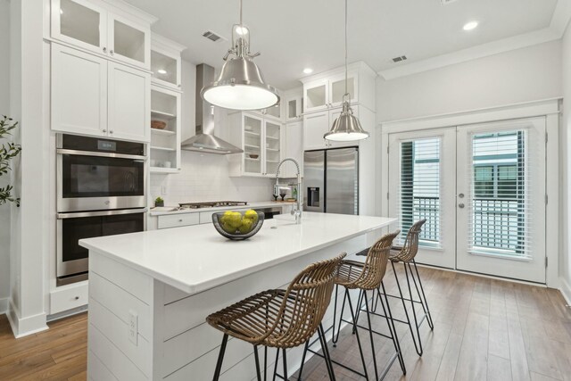 kitchen with glass insert cabinets, a kitchen island with sink, light countertops, and stainless steel appliances