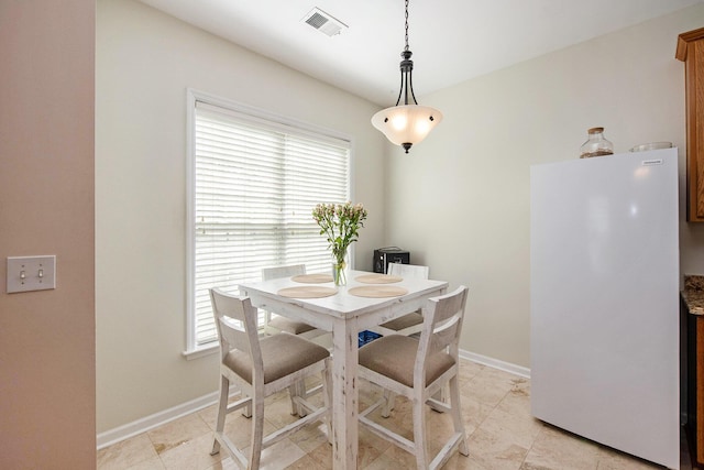 dining area featuring baseboards, visible vents, and a healthy amount of sunlight