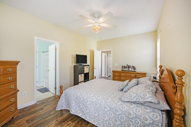 bedroom featuring ceiling fan, ensuite bath, dark wood-style floors, and baseboards