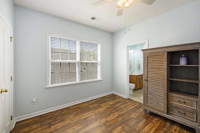 unfurnished bedroom featuring a sink, connected bathroom, visible vents, baseboards, and dark wood-style floors