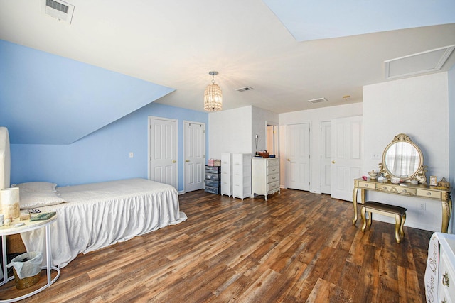 bedroom featuring wood finished floors, visible vents, and two closets