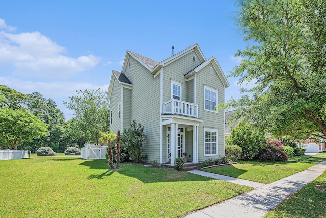 traditional home with fence, a front lawn, a gate, and a balcony