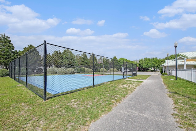 view of tennis court featuring fence, a lawn, and community basketball court