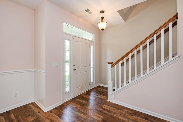 entrance foyer featuring plenty of natural light, visible vents, stairway, and dark wood finished floors