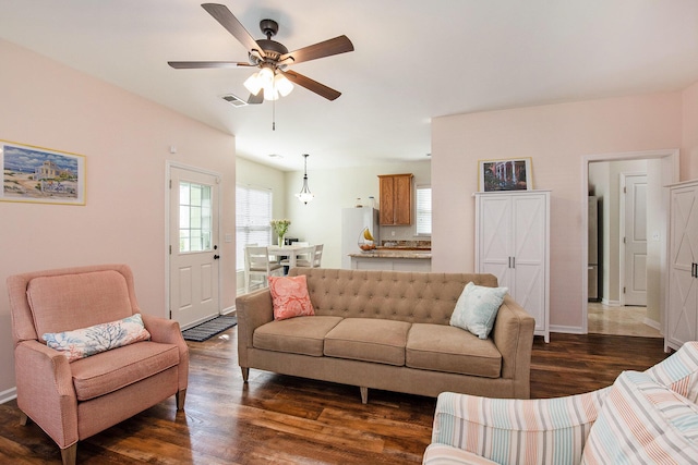 living room with baseboards, visible vents, ceiling fan, and dark wood-style flooring