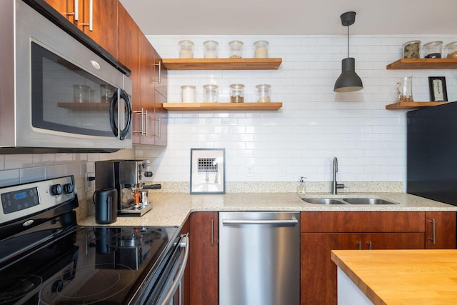 kitchen with hanging light fixtures, wooden counters, sink, appliances with stainless steel finishes, and decorative backsplash