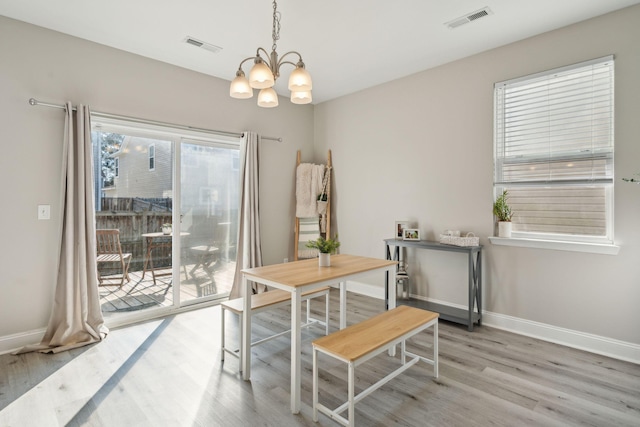 dining area with a chandelier, light wood-type flooring, visible vents, and baseboards