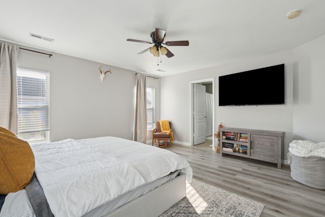 bedroom with light wood-style floors, visible vents, ceiling fan, and baseboards