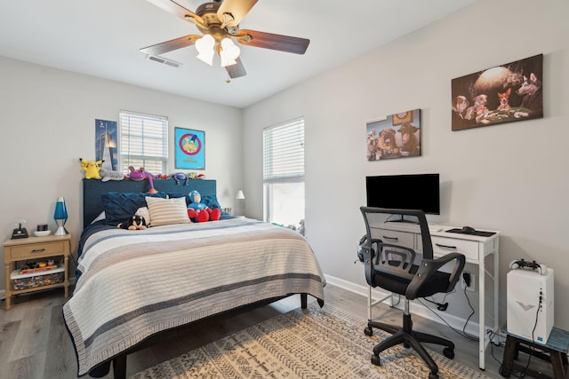 bedroom featuring multiple windows, visible vents, baseboards, and wood finished floors