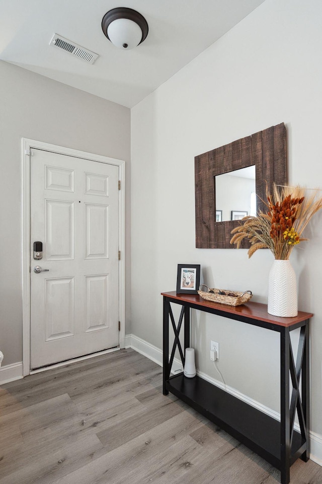 foyer entrance with wood finished floors, visible vents, and baseboards