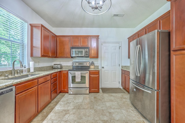 111 Kapalua Run, Summerville, SC 29483 - kitchen with stainless steel appliances, a sink, light stone countertops, a chandelier, and a textured ceiling