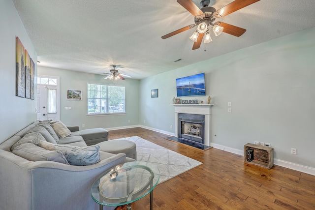 111 Kapalua Run, Summerville, SC 29483 - living room featuring ceiling fan, a fireplace with raised hearth, a textured ceiling, wood finished floors, and baseboards
